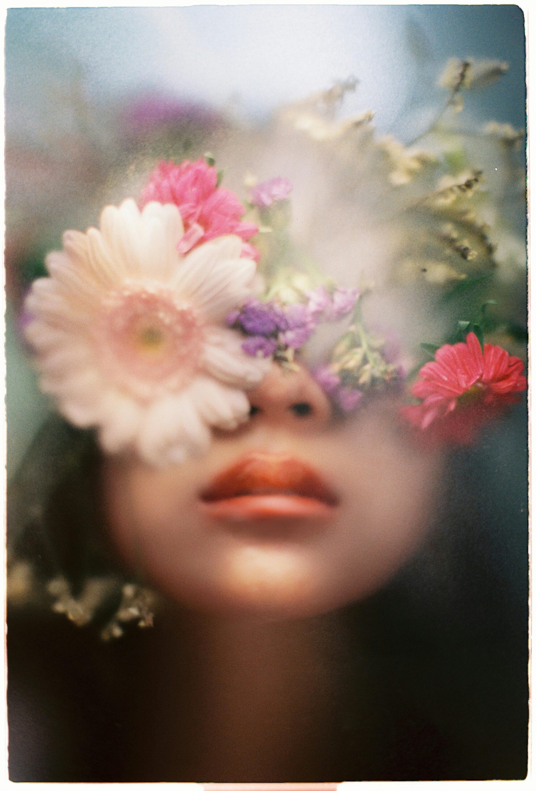 Close-up artistic portrait of a woman with soft-focus florals obscuring her eyes—representing creative branding for wedding photographers using SEO to attract modern, visually-driven clients.
