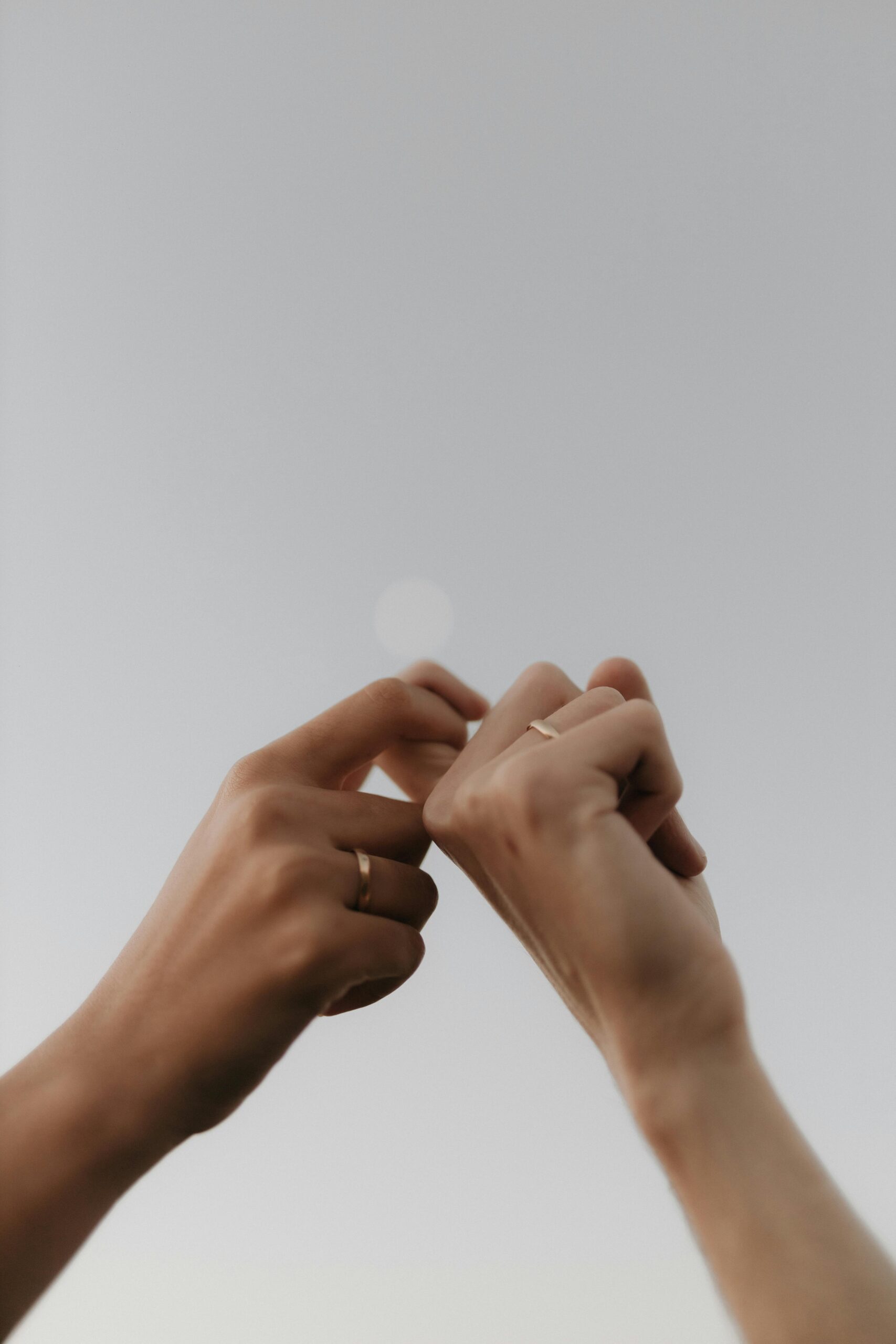 Close-up of two hands gently linking fingers with simple gold rings, symbolizing connection, commitment, and trust — echoing the intentional foundation photographers need before using AI for marketing or SEO.