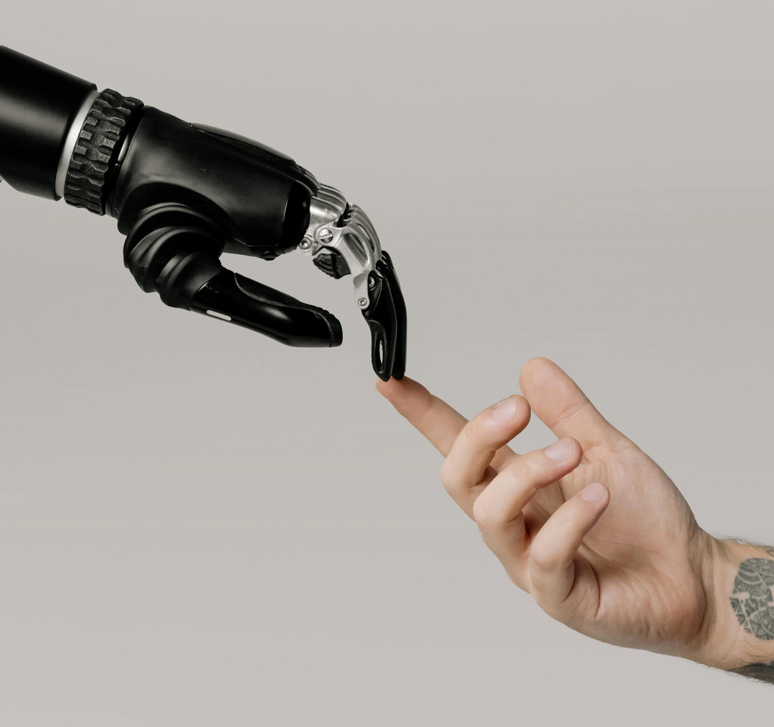 Close-up of a human hand reaching out to touch a robotic hand, symbolizing the connection between people and artificial intelligence.